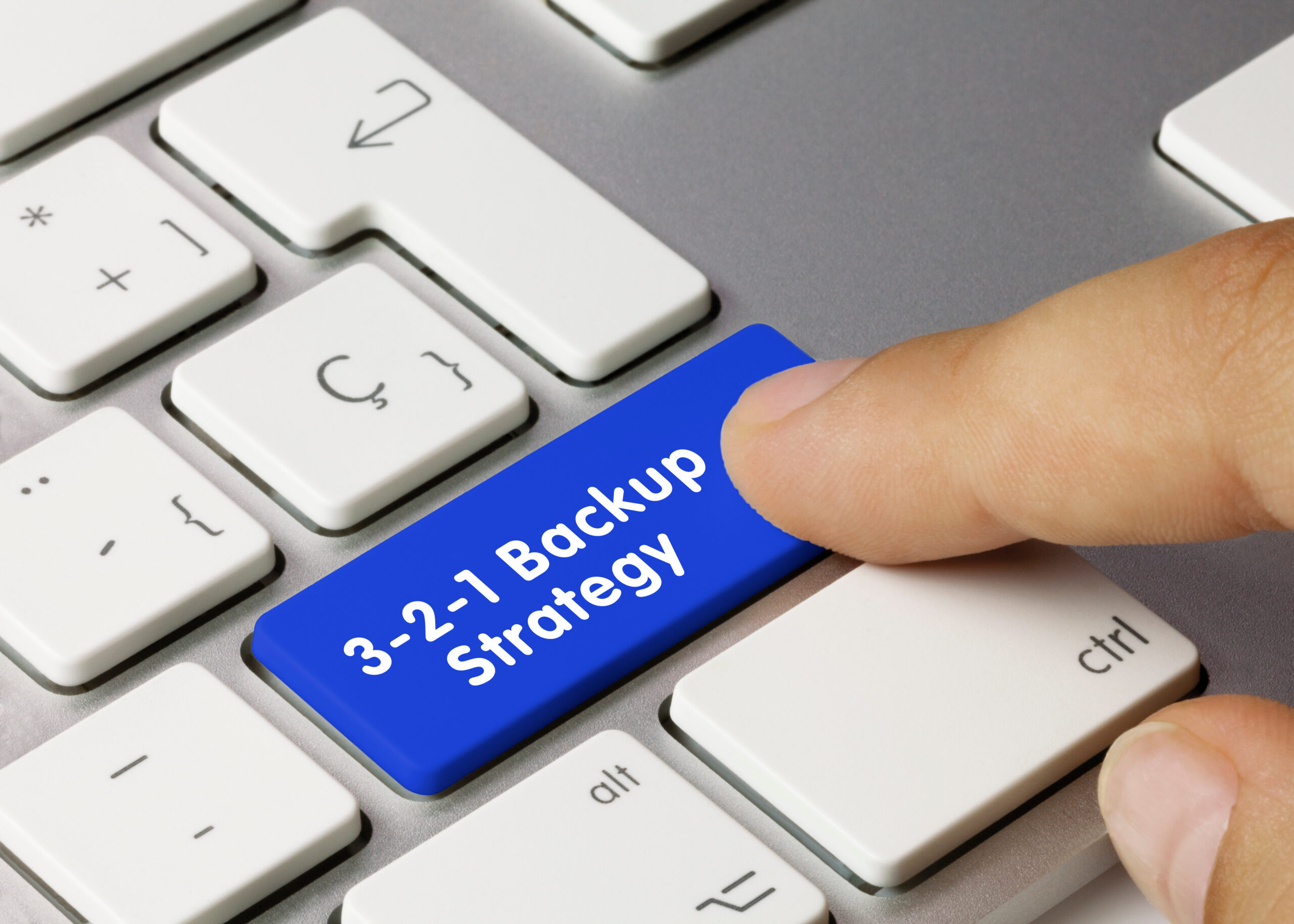 3-2-1 Backup Strategy Written on Blue Key of Metallic Keyboard. Finger pressing key.